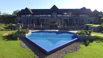 Een buitenzwembad, parasols bij het zwembad en ligstoelen