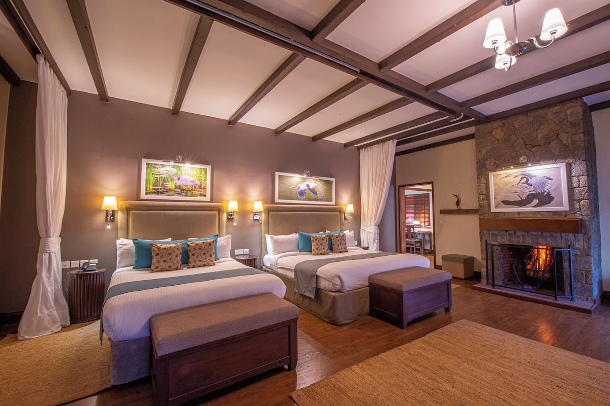 Une chambre d’hôtel avec deux lits, une cheminée et des œuvres d’art aux murs.