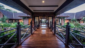 A wooden bridge leading to a row of rooms with a brick facade, surrounded by greenery. - The Retreat at Ngorongoro (Karatu)