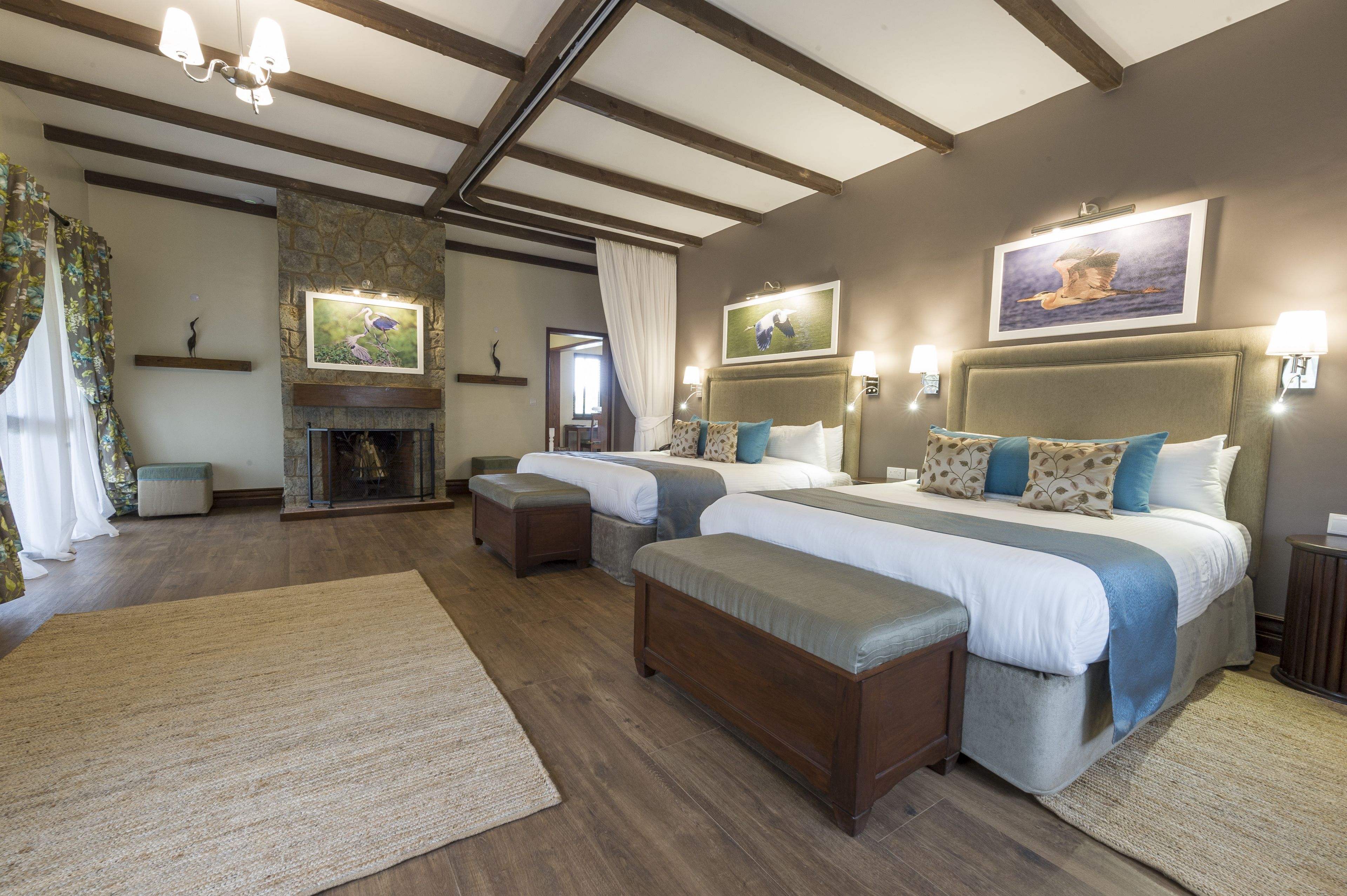 Habitación de hotel con dos camas, chimenea y obras de arte en las paredes.