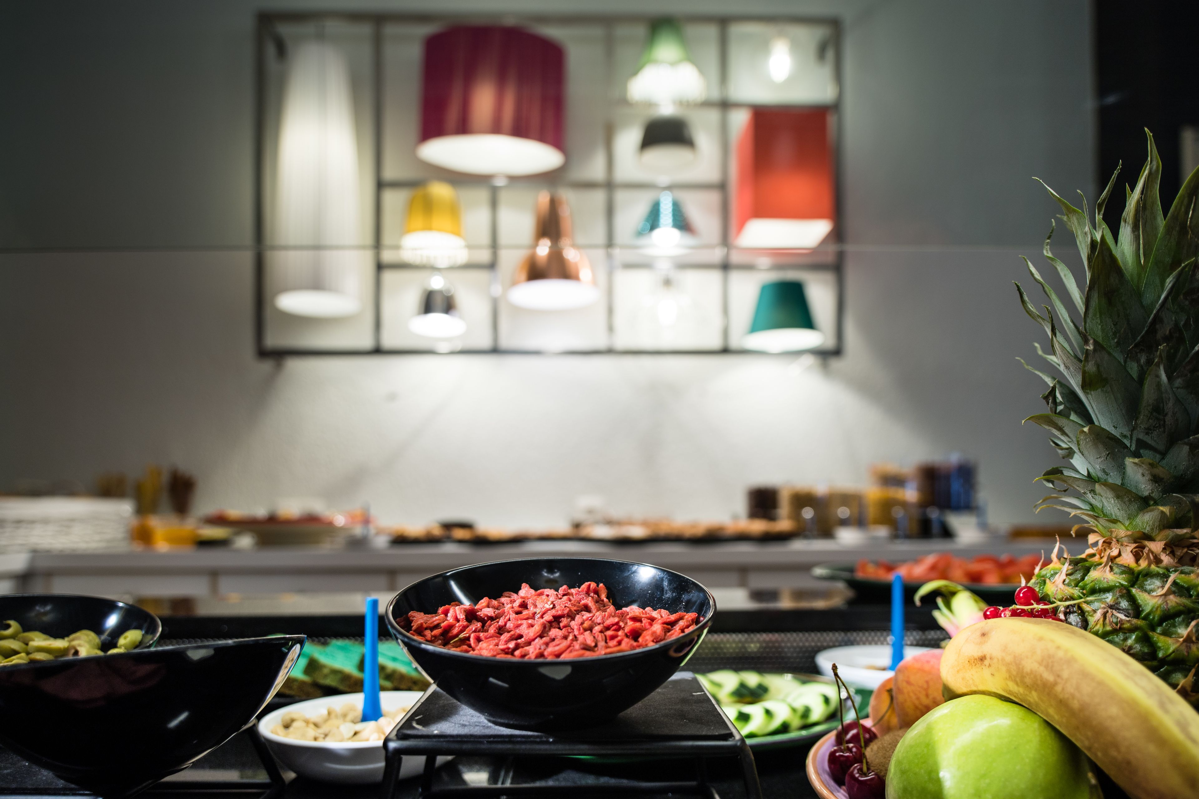 A kitchen counter with a bowl of meat, various fruits, and a pineapple.