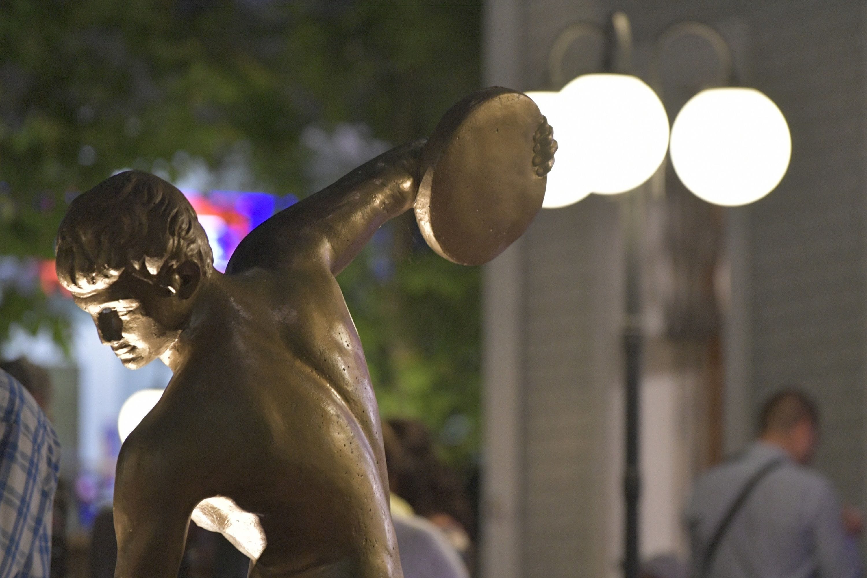 Una statua in bronzo raffigura un uomo che tiene un disco.