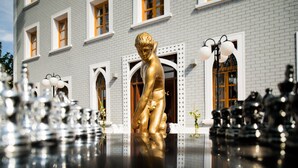 A golden statue in front of a building with multiple windows and a reflective floor. - A for Art Design Hotel (Thasos)