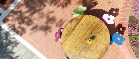A round wooden table surrounded by colorful chairs with cut-out shapes.