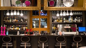A bar area with multiple liquor bottles, a cash register, and bar stools. - A for Art Design Hotel (Thasos)