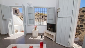 A room with a TV, a wine bottle, and two glasses on a table. - Skyline Villa (Santorini)