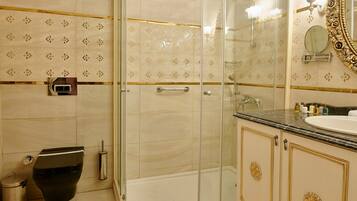 Un baño con ducha de vidrio, inodoro y lavamanos con encimera de mármol.