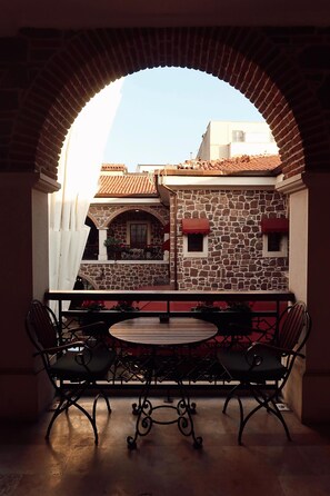 A balcony with a stone wall, a round table, and four chairs. - L'Agora Old Town Hotel & Bazaar (Izmir)