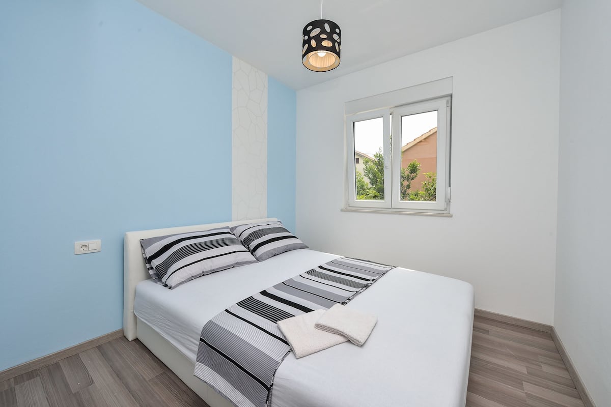 Un dormitorio con cama, ventana y lámpara.