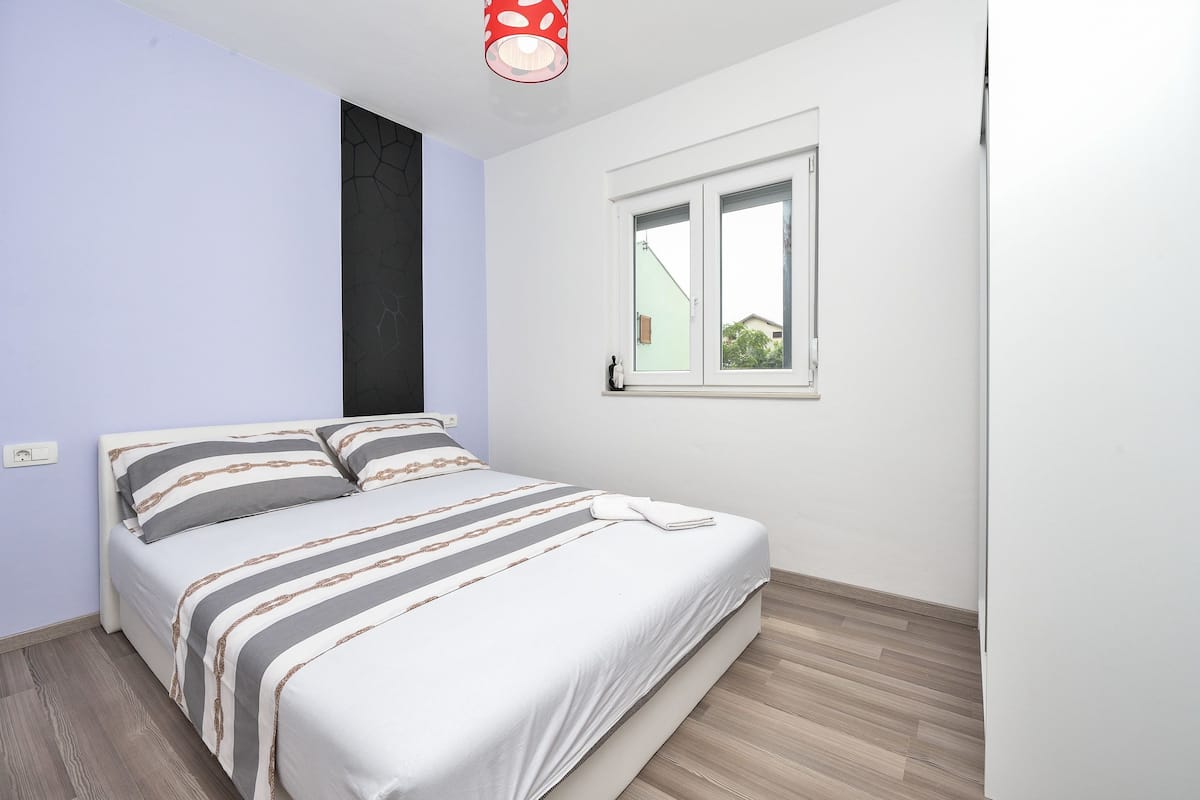 Un dormitorio con una cama, una ventana y una lámpara.