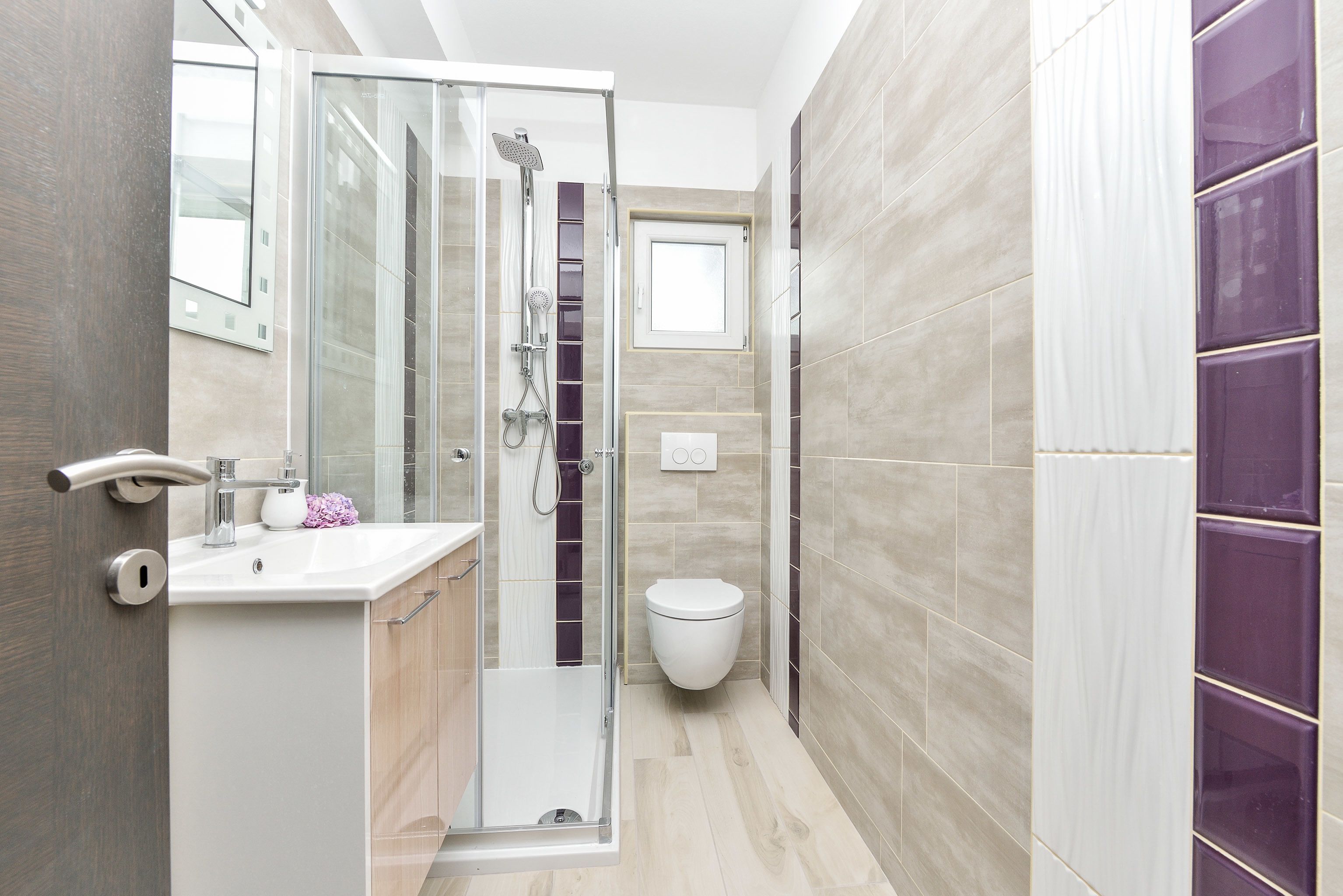 A modern bathroom with a glass shower enclosure, a white sink, and a toilet.