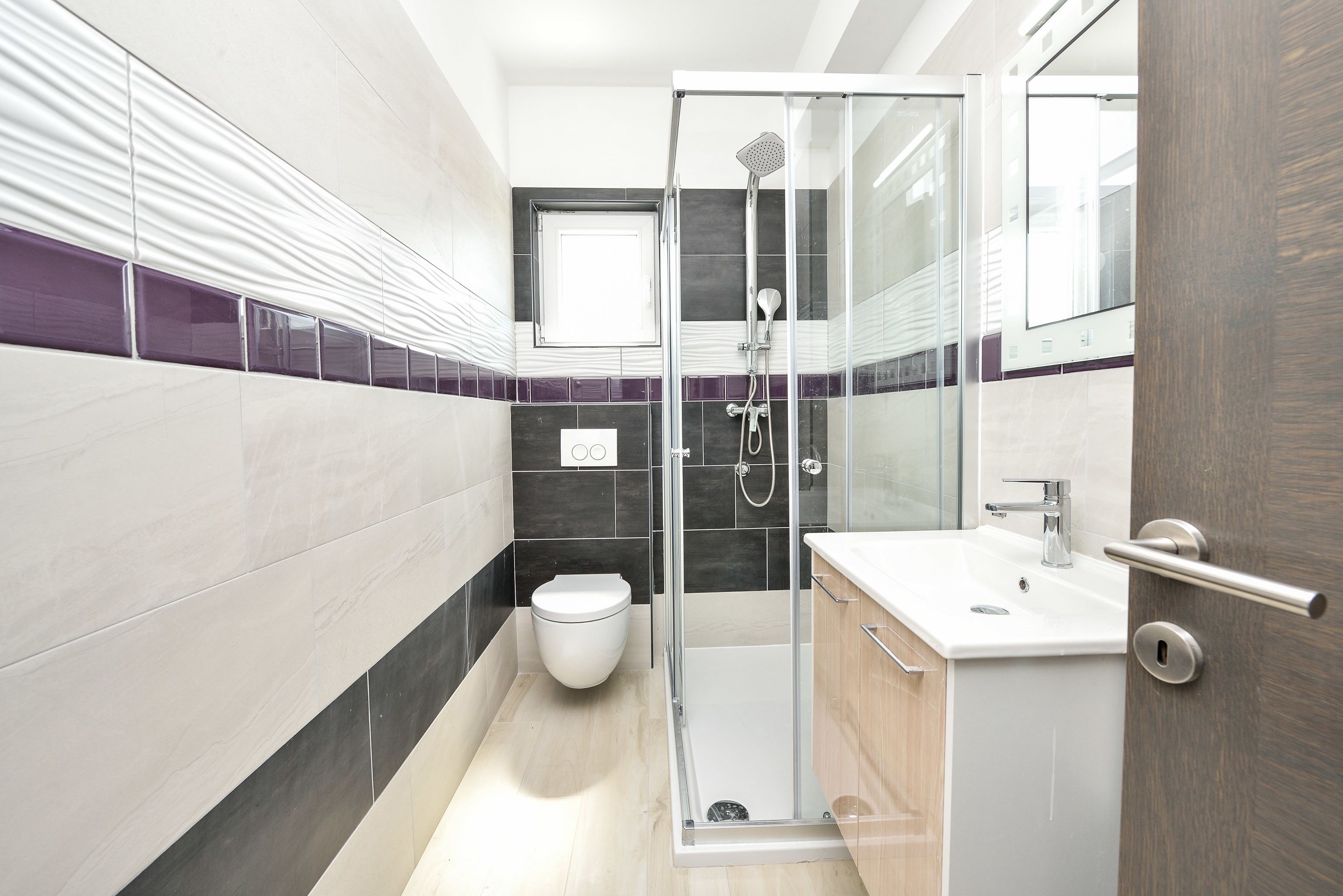 A modern bathroom with a glass-enclosed shower, a white sink, and a toilet.