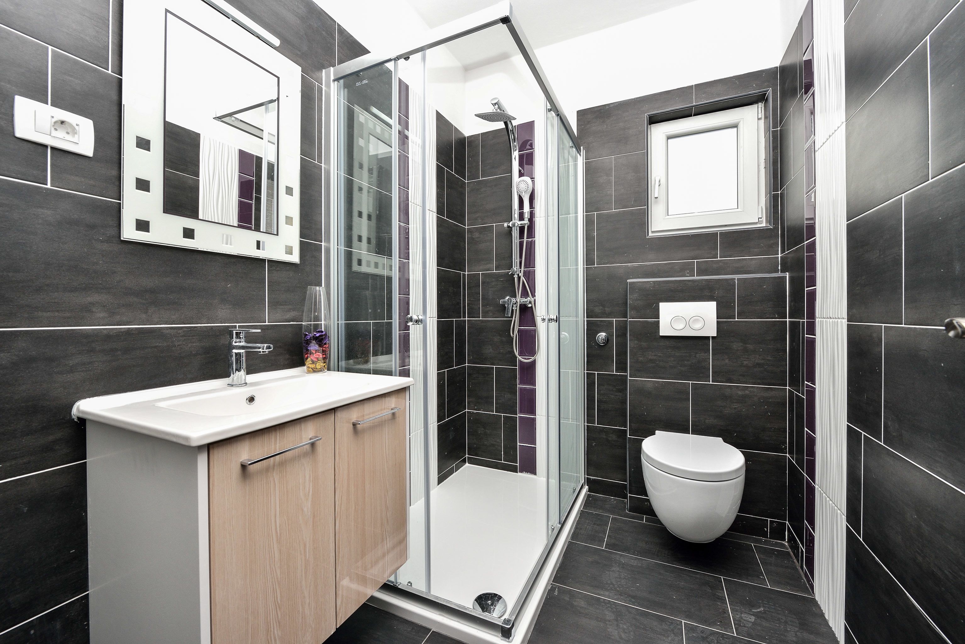 A modern bathroom with a glass shower enclosure, a white sink, and a toilet.