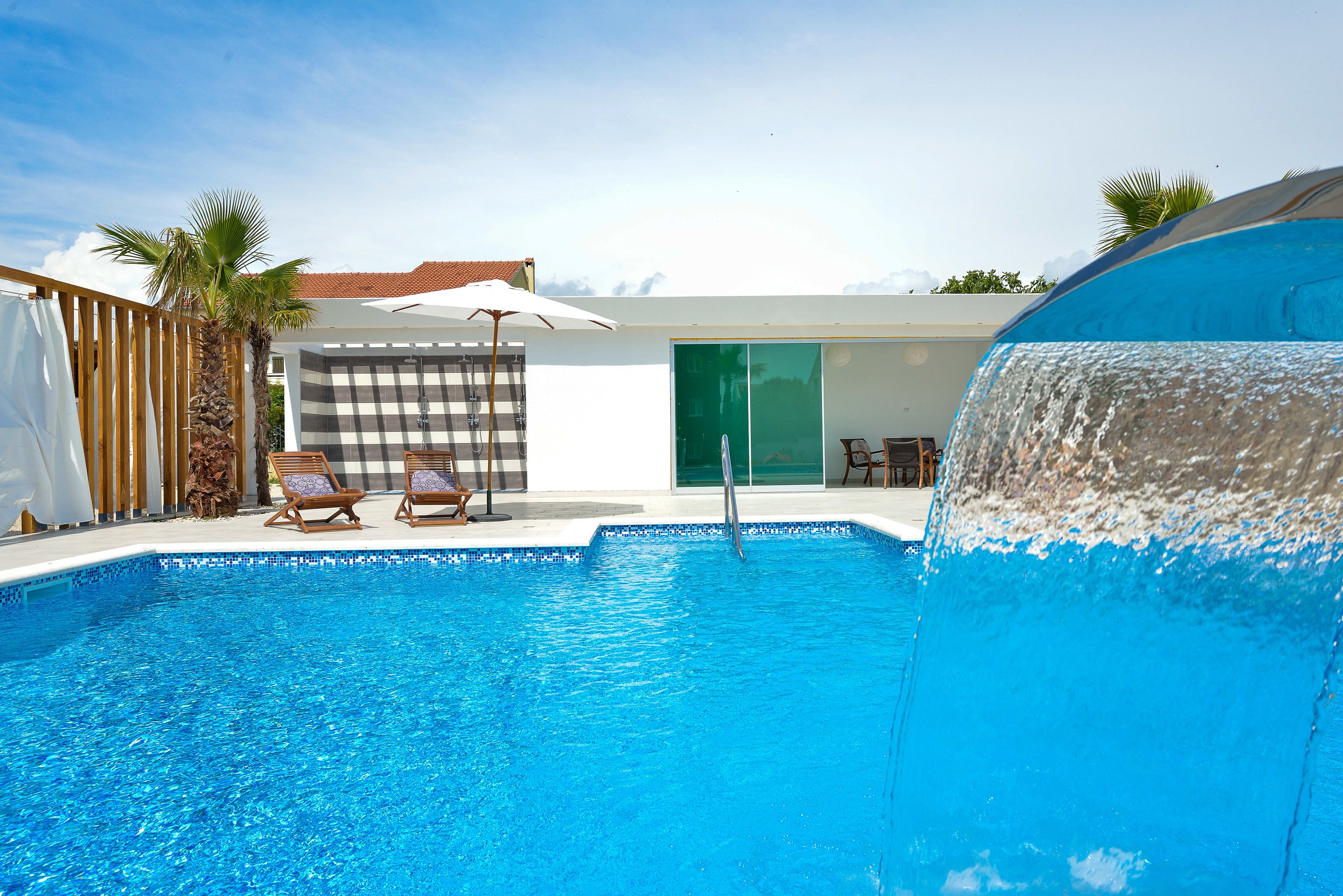 Una piscina con sillas de descanso y un tobogán de agua.