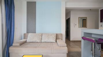 A modern living room with a beige sofa, a small yellow table, and a purple bar stool.