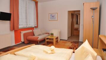 Ein Hotelzimmer mit Bett, Sofa, kleinem Tisch, Fernseher und Kleiderschrank.