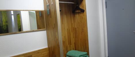 Ein Holzschrank mit Spiegel, ein grünes Handtuch und eine Bank.