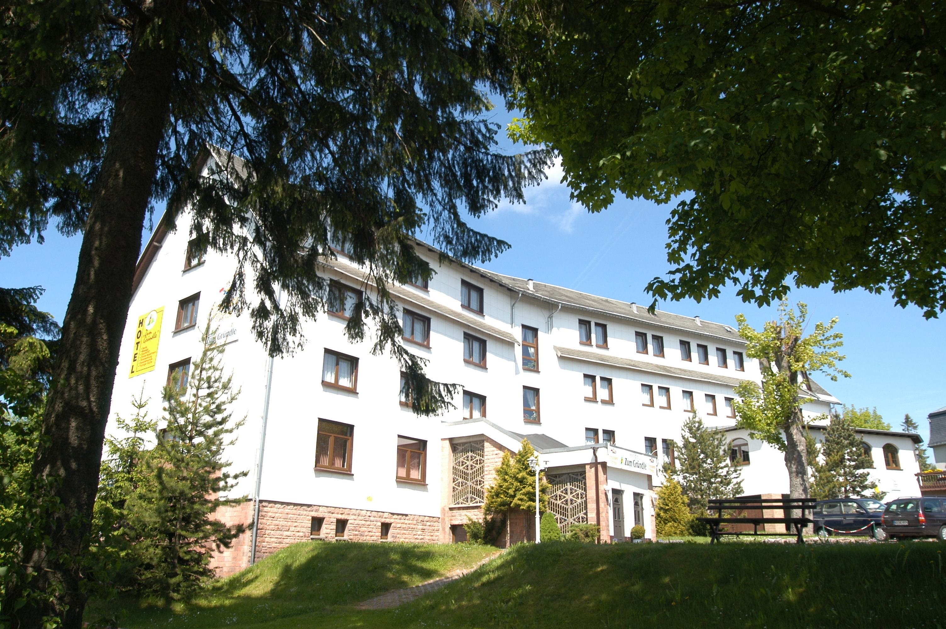 A multi-story hotel with a white facade, multiple windows, and a visible entrance.