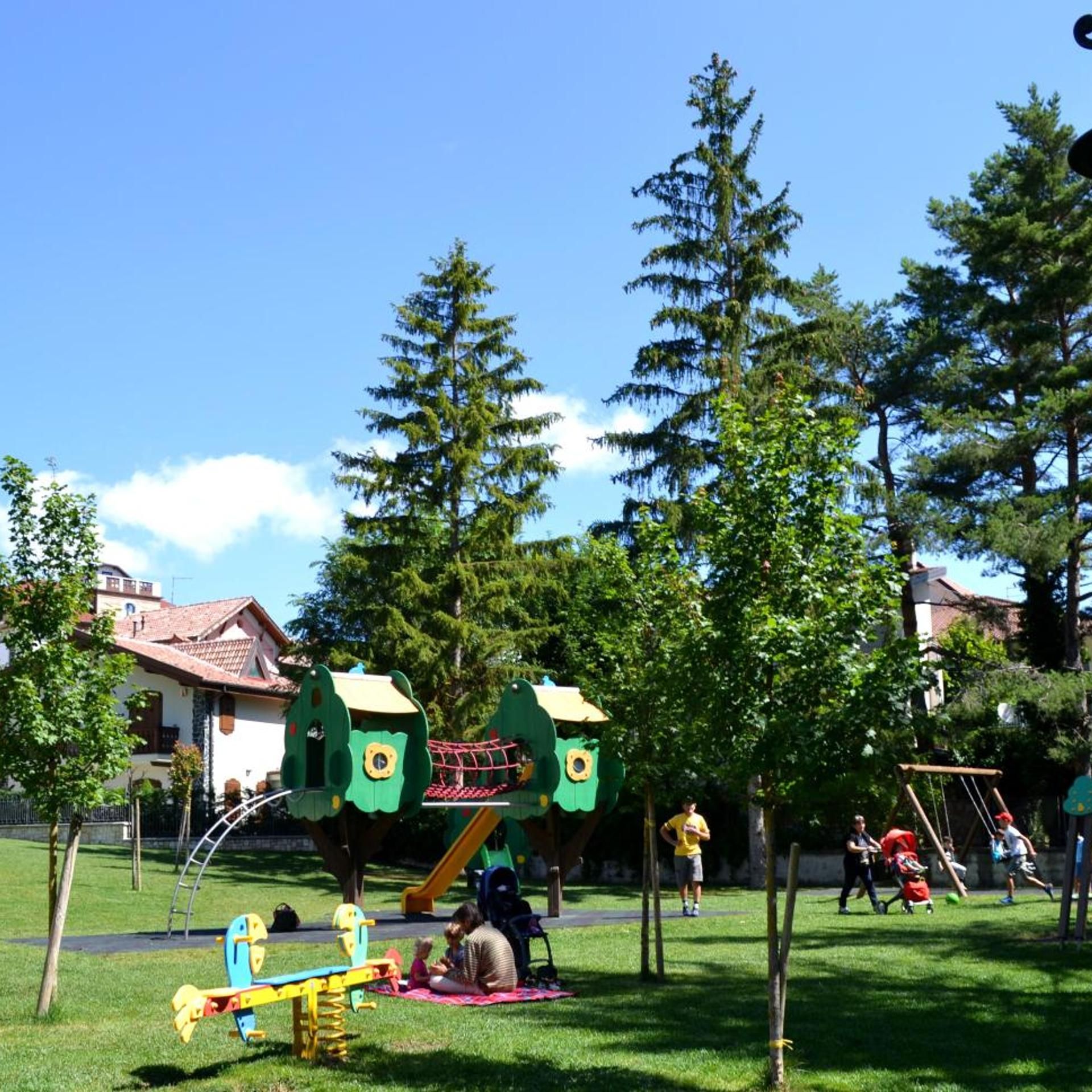 Ein Spielplatz mit grünen Spielgeräten, einer Wippe und einer Rutsche.