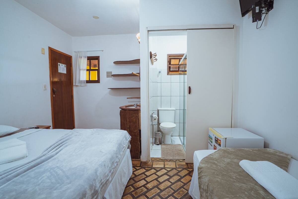 A hotel room with two beds, a bathroom, and a small kitchenette.