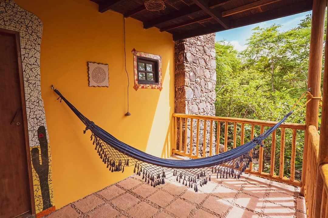 Un hamac sur un balcon, avec un mur en pierre et une balustrade en bois.