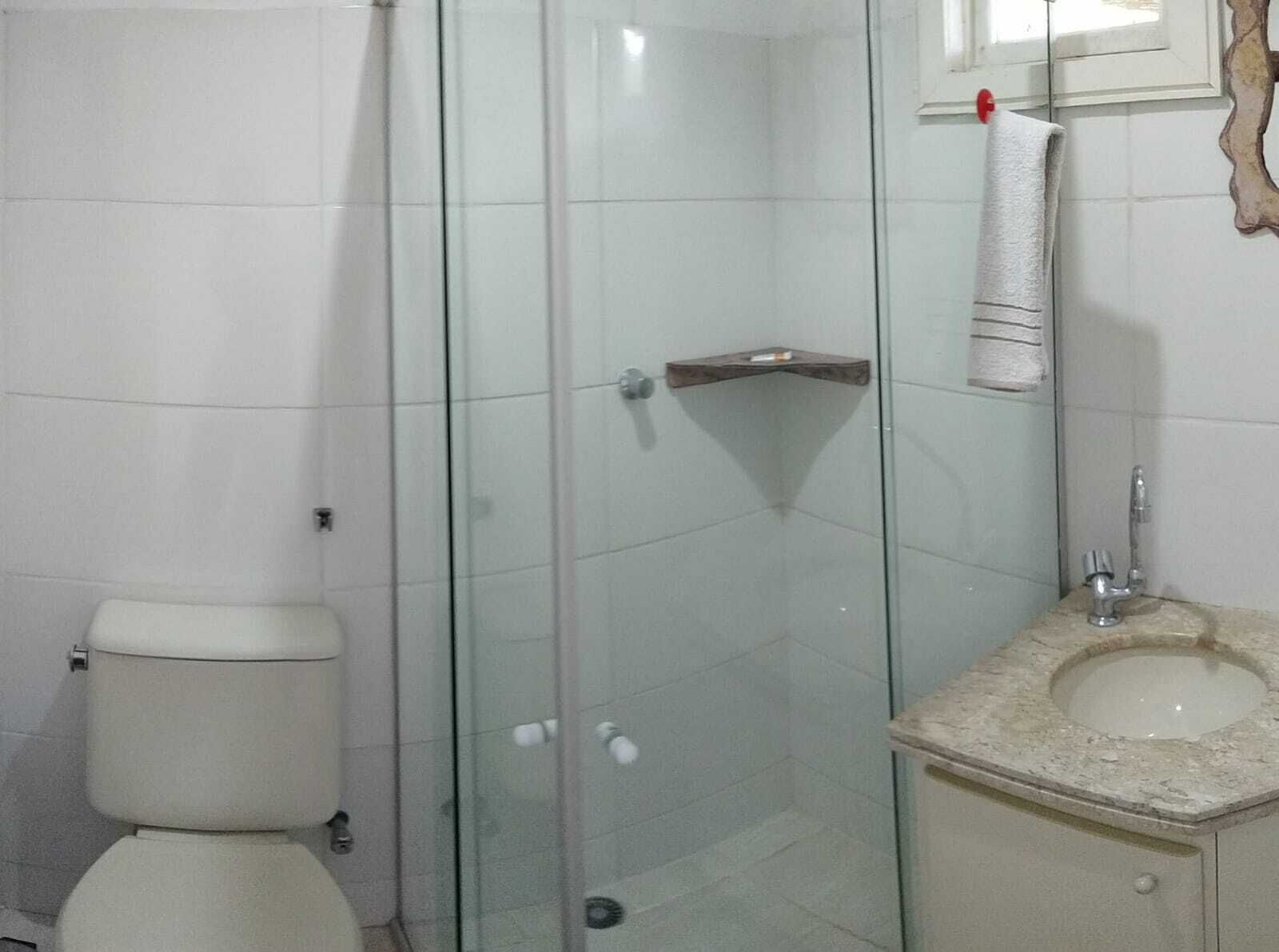 Une salle de bain comprenant des toilettes, une douche à parois de verre, un lavabo avec un plan de toilette en marbre et une serviette suspendue à un porte-serviettes.