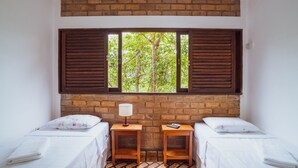 A room with two beds, a brick wall, and a window with shutters. - Pousada Alto do Cajueiro (Lençóis)