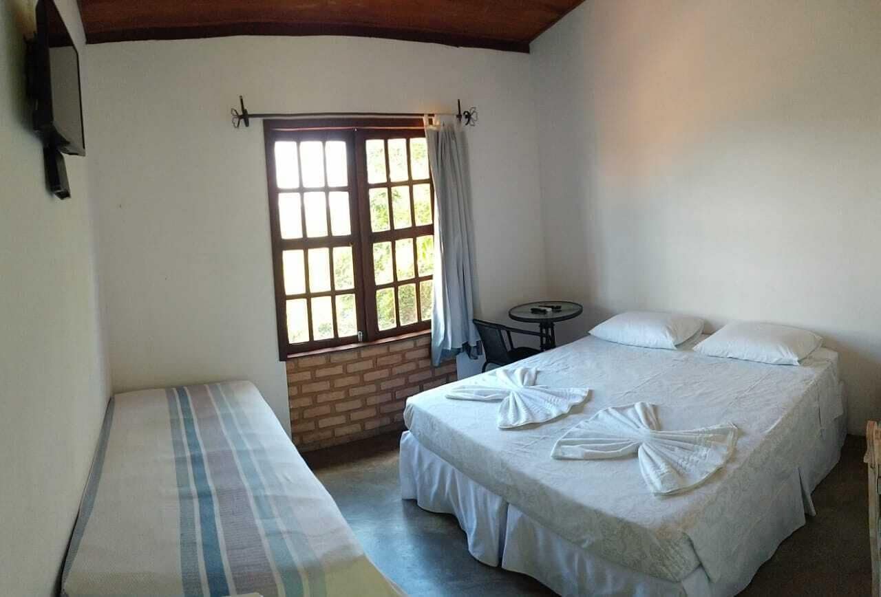 A room with a bed, a small table, and a window with curtains.