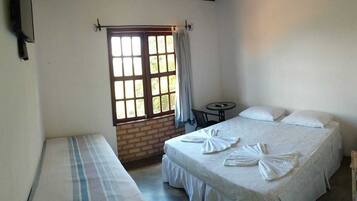 A room with a bed, a small table, and a window with curtains.