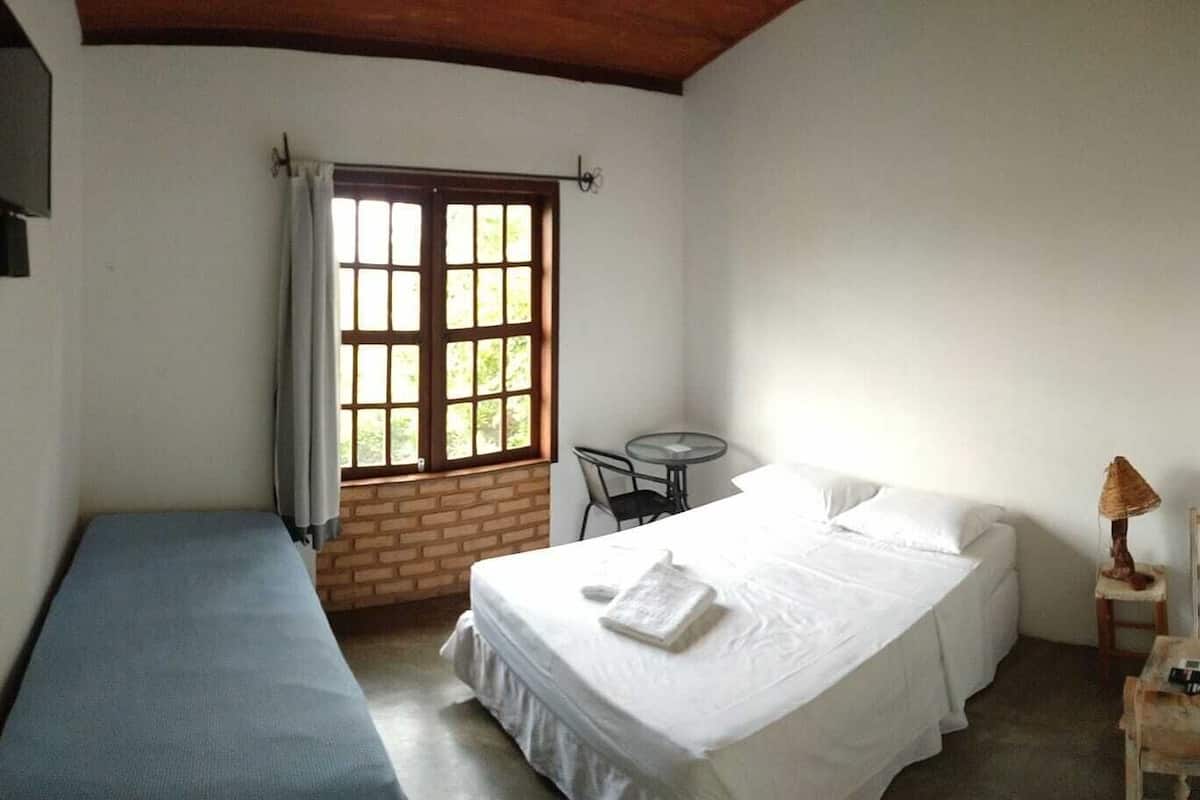A room with a bed, a small table, and a window with curtains.