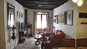 A cozy living room with a fireplace, wooden furniture, and framed pictures on the walls. - Casa Rural Las Piedras (Grazalema)