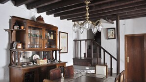 A dining area with a wooden table, chairs, a cabinet with glass doors, and a chandelier. - Casa Rural Las Piedras (Grazalema)