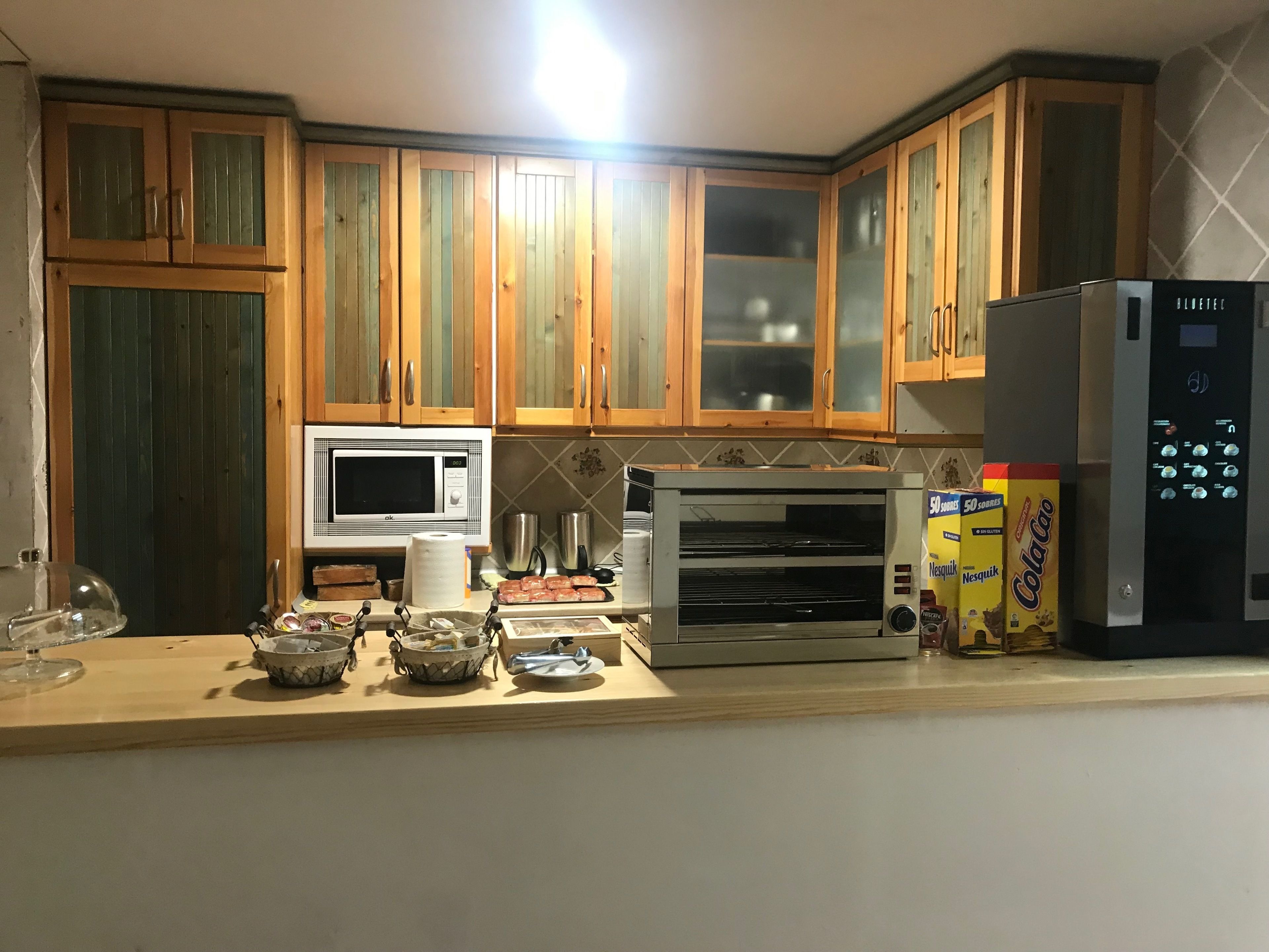 Una cocina con armarios de madera, microondas, horno tostador y refrigerador.
