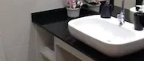 A bathroom with a white sink, black countertop, and a mirror.