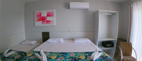 Camera d'albergo con un letto grande, un comodino, una sedia, un armadio e un condizionatore d'aria.