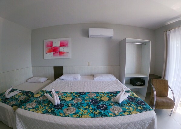 Habitación de hotel con una cama grande, una mesita de noche, una silla, un armario y un equipo de aire acondicionado.