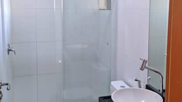 Une salle de bain moderne avec une douche à parois de verre, des toilettes blanches et un plan de toilette noir avec un lavabo blanc.