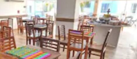Un comedor amplio con mesas y sillas de madera, una isla central con mostrador y vistas al exterior.