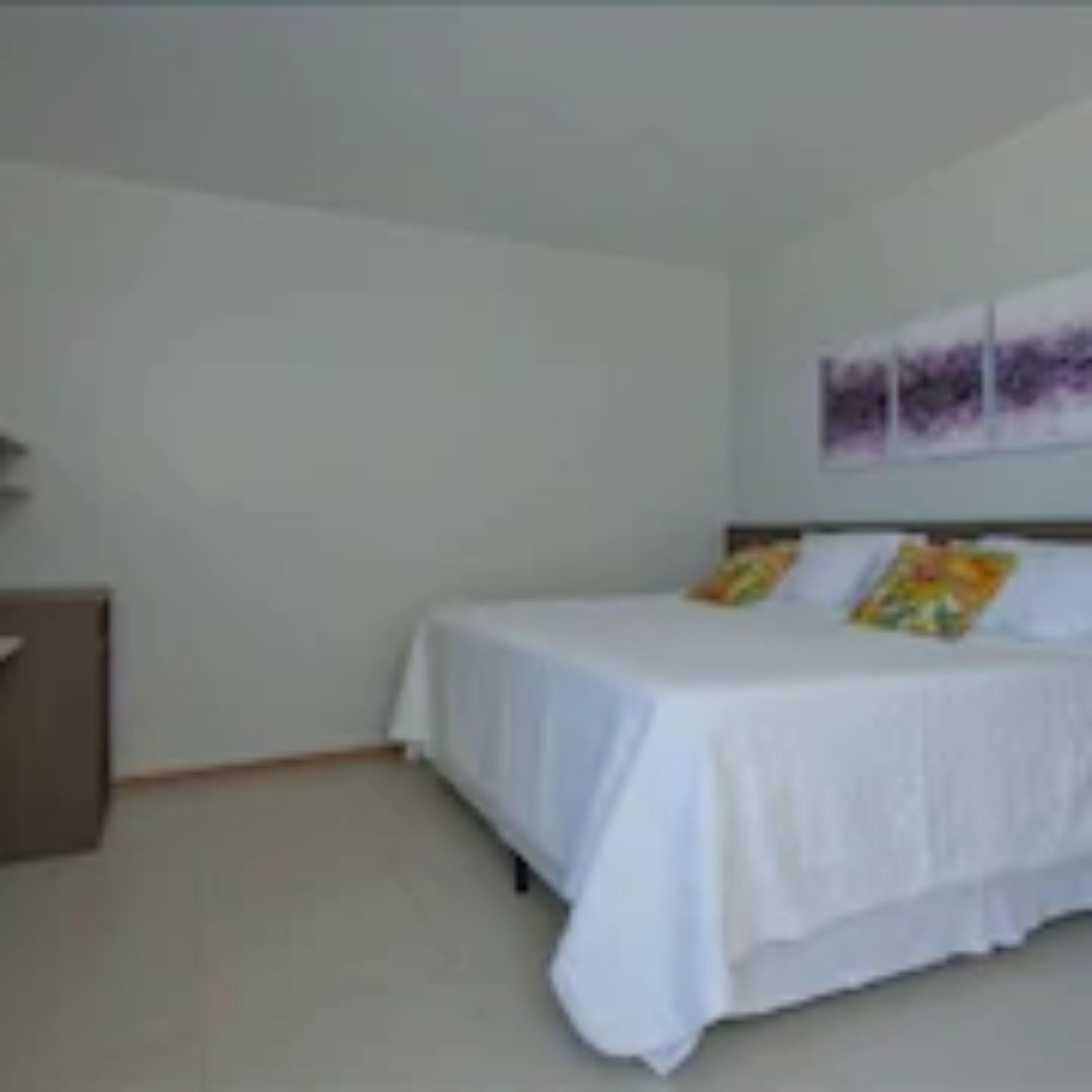 Un dormitorio con cama, mesita de noche y repisa en la pared.
