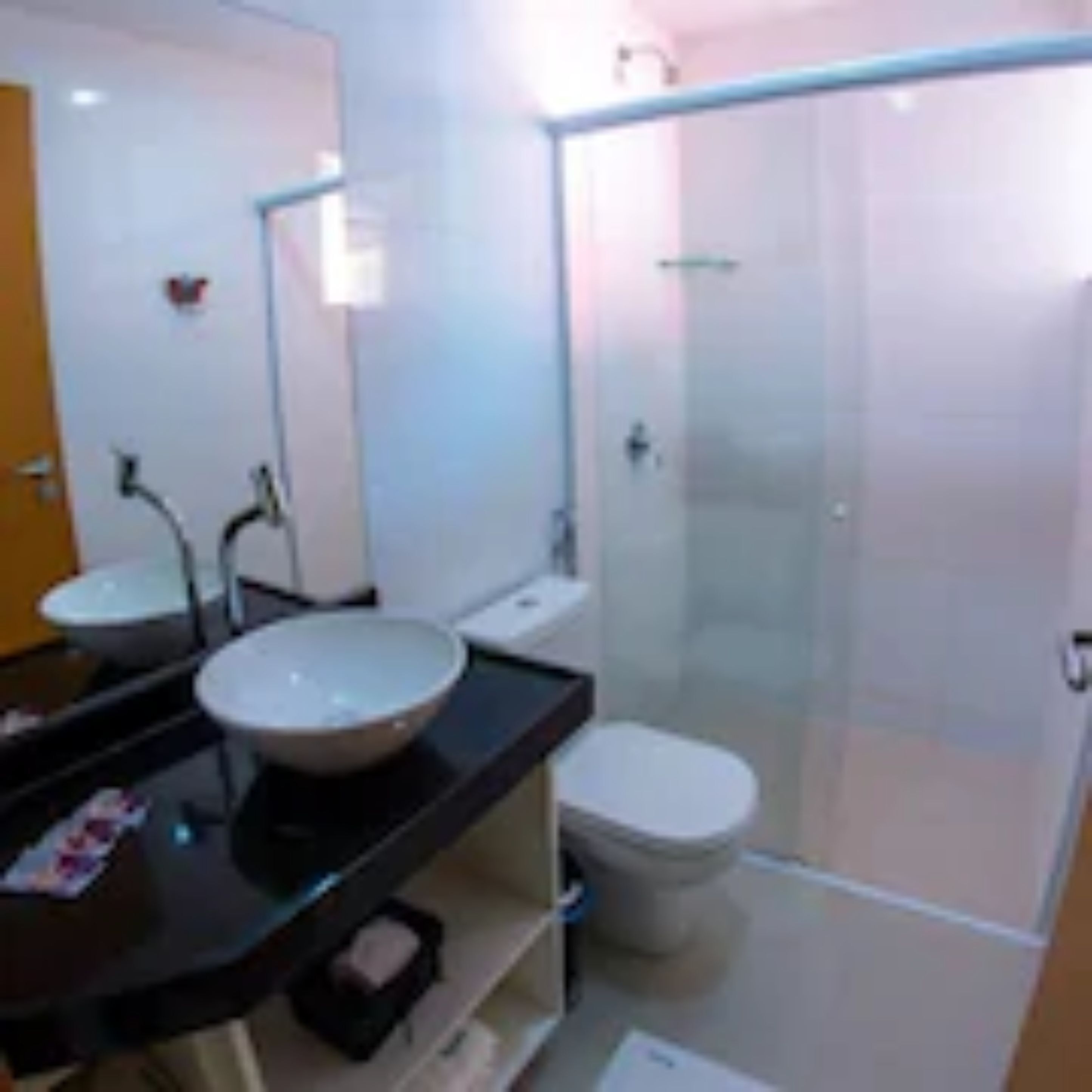 A modern bathroom with a glass-enclosed shower, a double sink vanity, and a toilet.