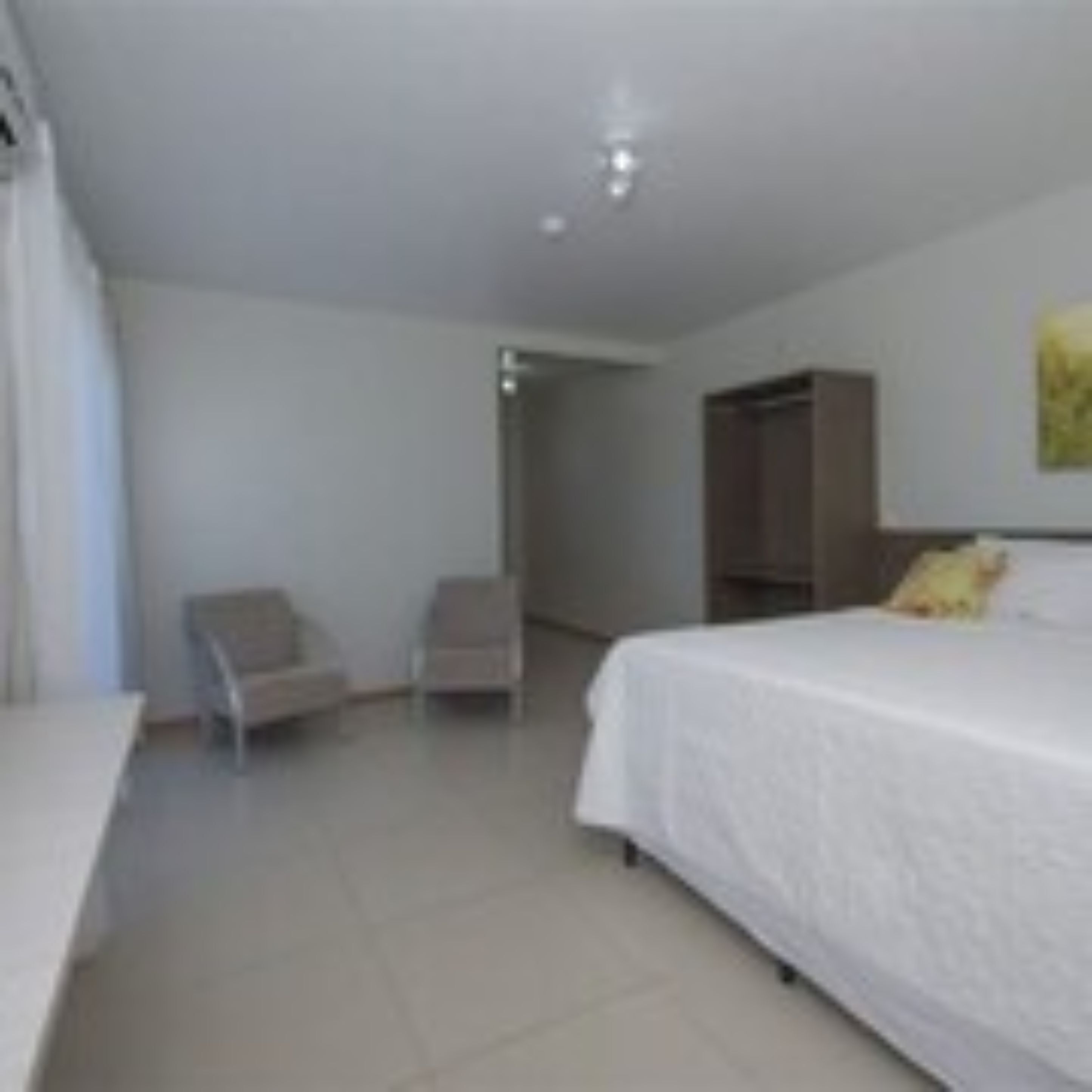 A hotel room with a bed, a chair, and a wardrobe.