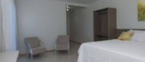 A hotel room with a bed, a chair, and a wardrobe.