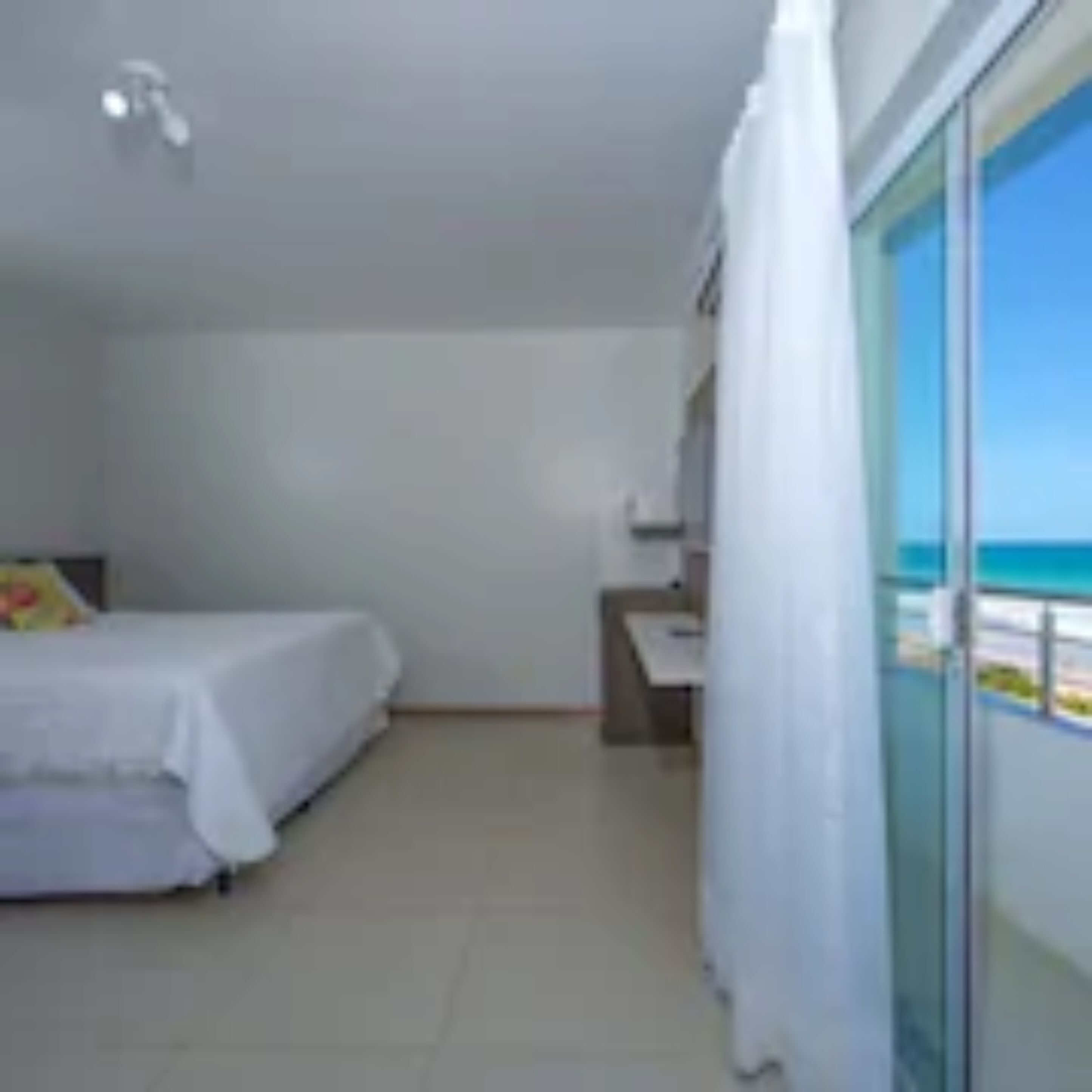 Une chambre avec un lit, un bureau et une vue sur la plage.