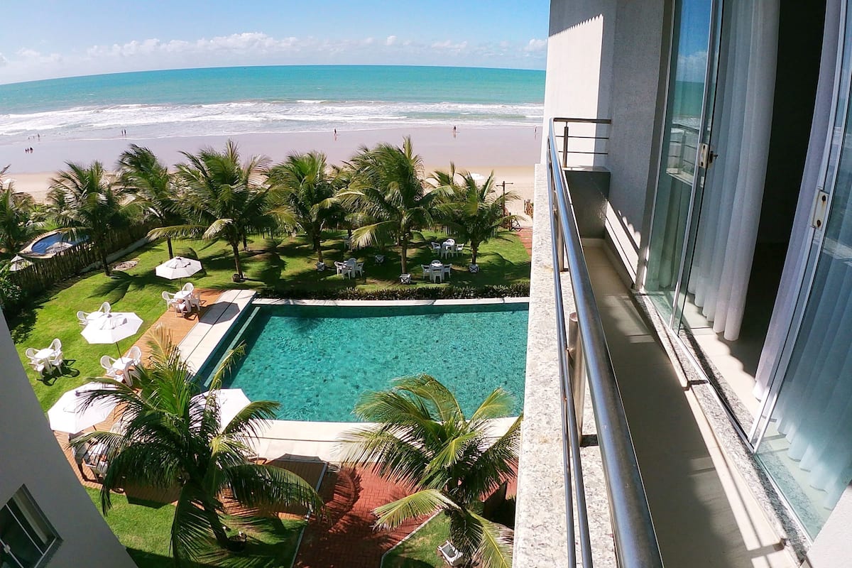 A balcony with a view of a swimming pool and beach.