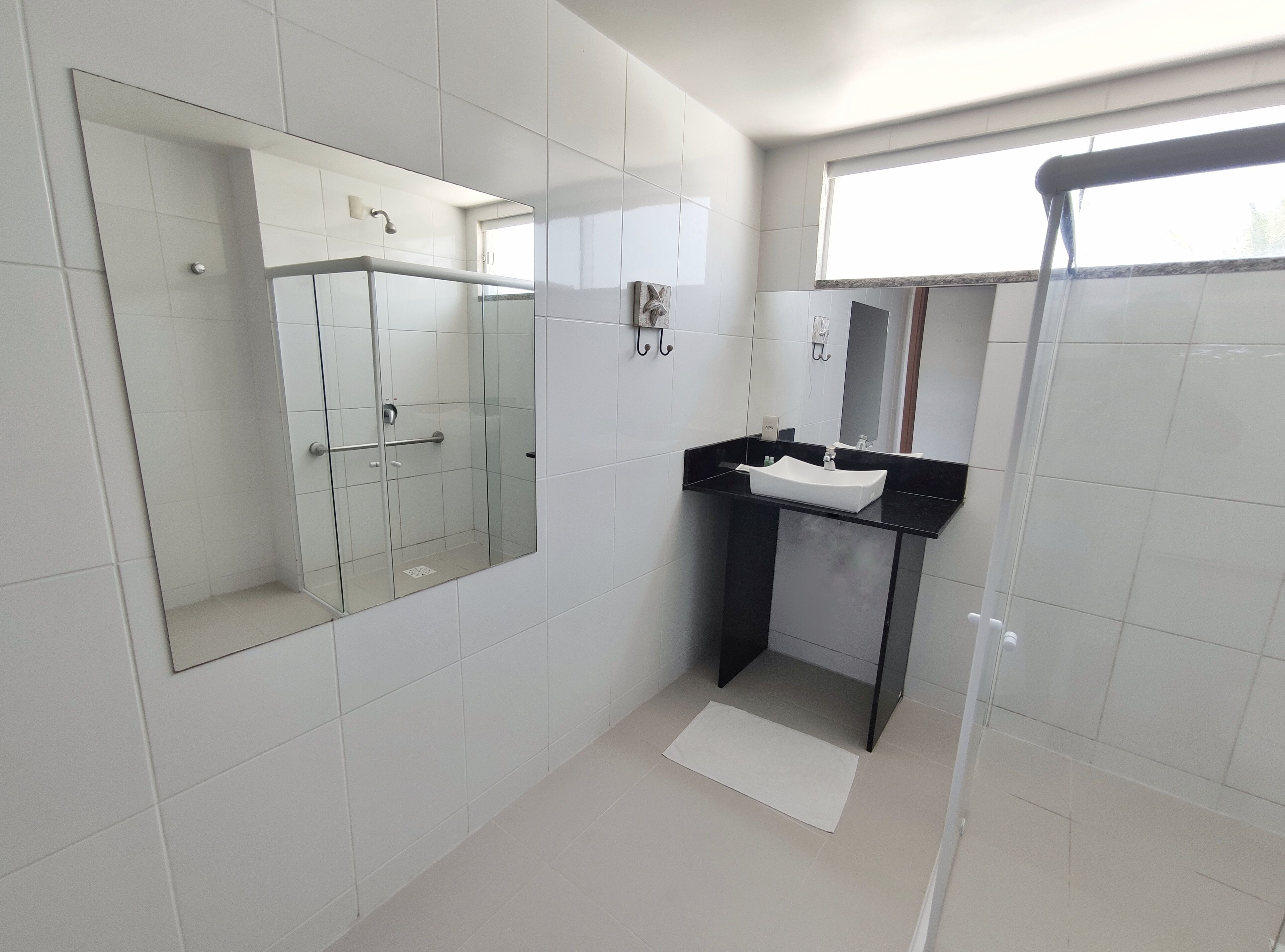 A modern bathroom with a glass shower enclosure, a black countertop sink, and a large mirror.