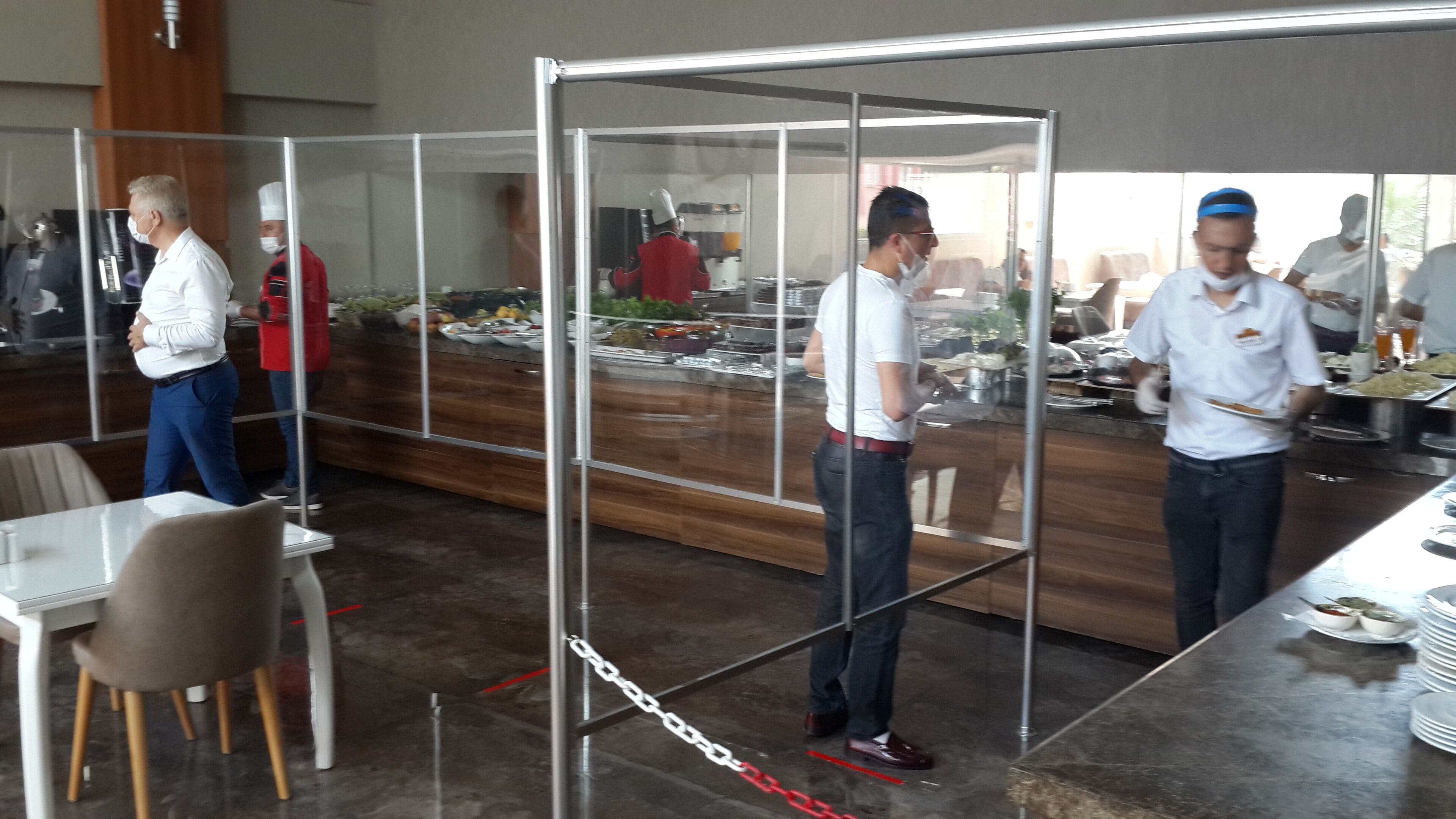 Une salle de conférence avec une cloison en verre, une table de buffet garnie de divers plats et un espace détente avec des chaises et une table.
