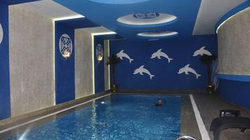An indoor swimming pool with dolphin wall art and a blue and grey color scheme.