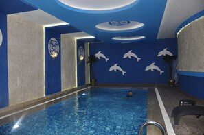 Una piscina interior con detalles de arte mural de delfines y una paleta de colores azul y gris.