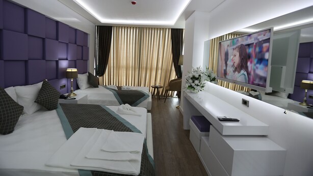 A modern hotel room with two beds, a TV, a desk, and a mirror. - Elips Royal Hotel & Spa (Antalya)