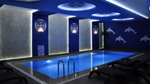 A modern indoor swimming pool with blue lighting, decorative wall panels, and dolphin motifs. - Elips Royal Hotel & Spa (Antalya)
